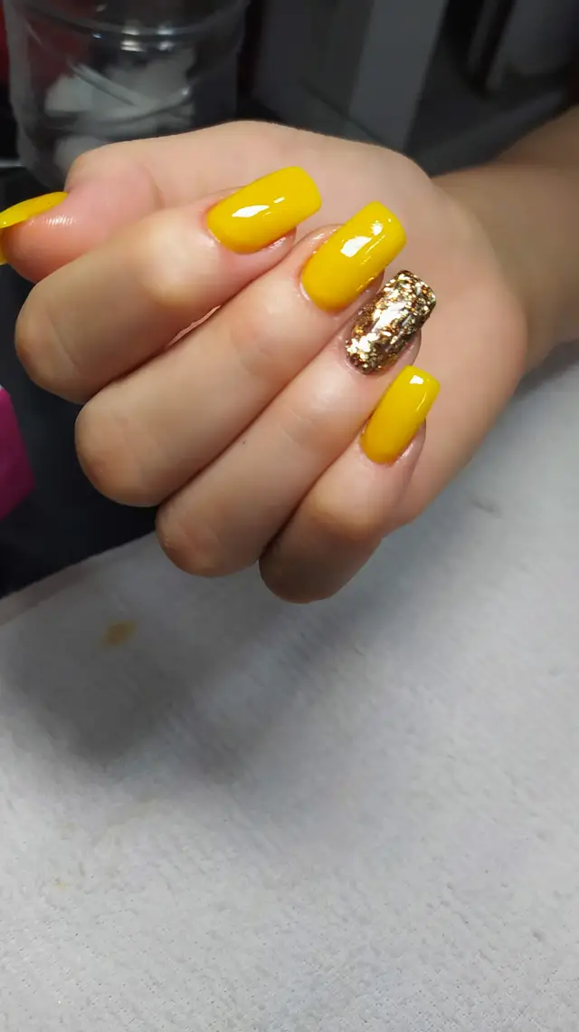 Uñas acrílicas amarillas con detalle dorado